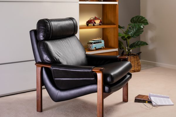 An elegant Tessa armchair upholstered with Black Leather, set in a living room.